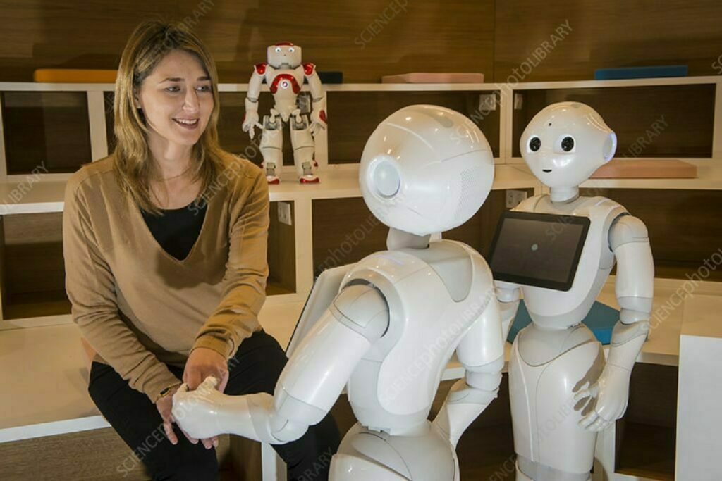 Editorial use only  
Researcher with two Pepper robots and a Nao robot (behind) built by SoftBank Robotics. Nao is an autonomous, programmable humanoid robot whose development began in 2004. Nao robots have been used for research purposes, and as interactive and educational assistants for children in hospital and elderly people in care homes. The Pepper robot was designed with the ability to read emotions and interact with people via its touch screen, and was introduced in 2014. It is in use in research and education, as well as in commercial settings.